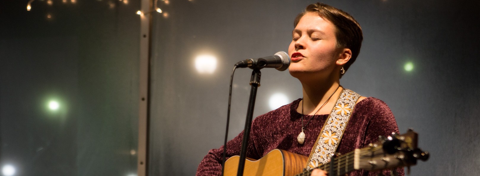 Vanessa Hale playing guitar and singing into a microphone