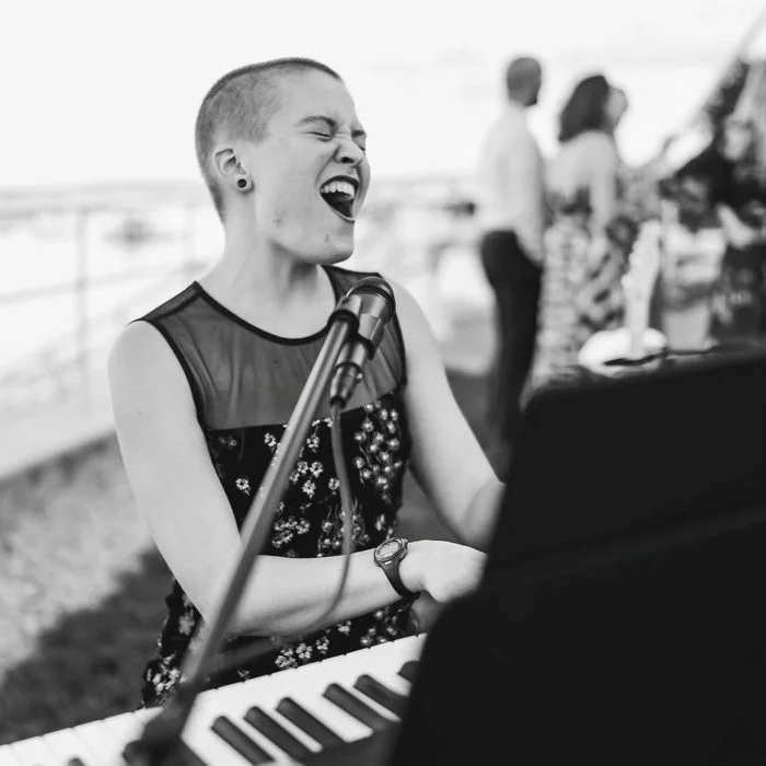 Vanessa Hale playing on piano, singing passionately