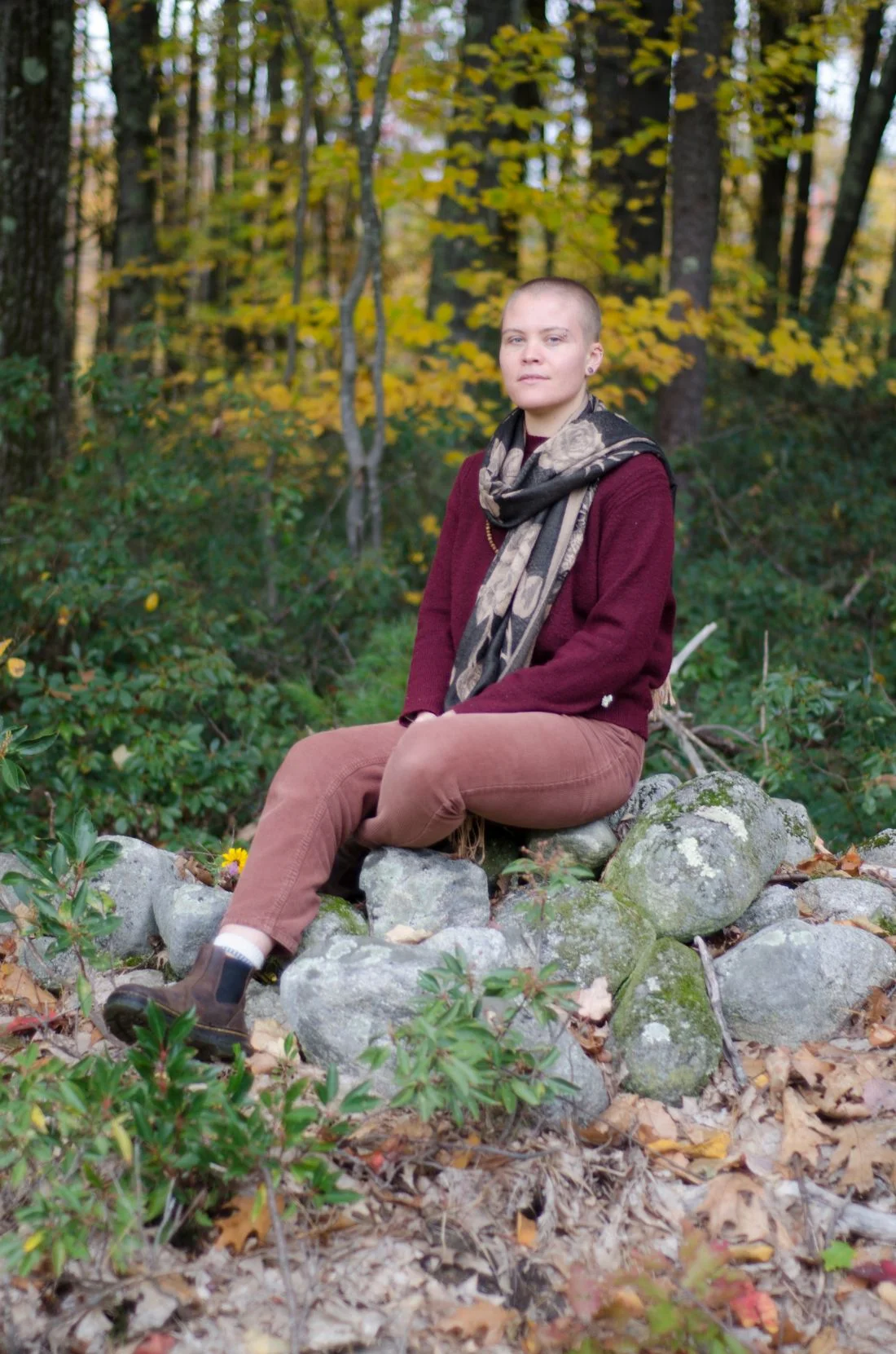 Vanessa Hale sitting on small hill of rocks with the forest int he background