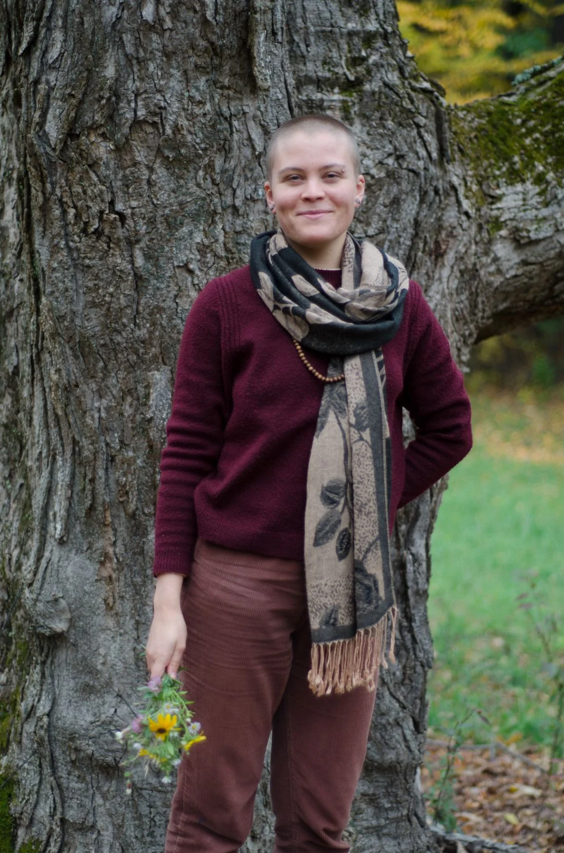 Vanessa Hale standing in front of a tree,holding a small bouquet of fresh picked wild flowers