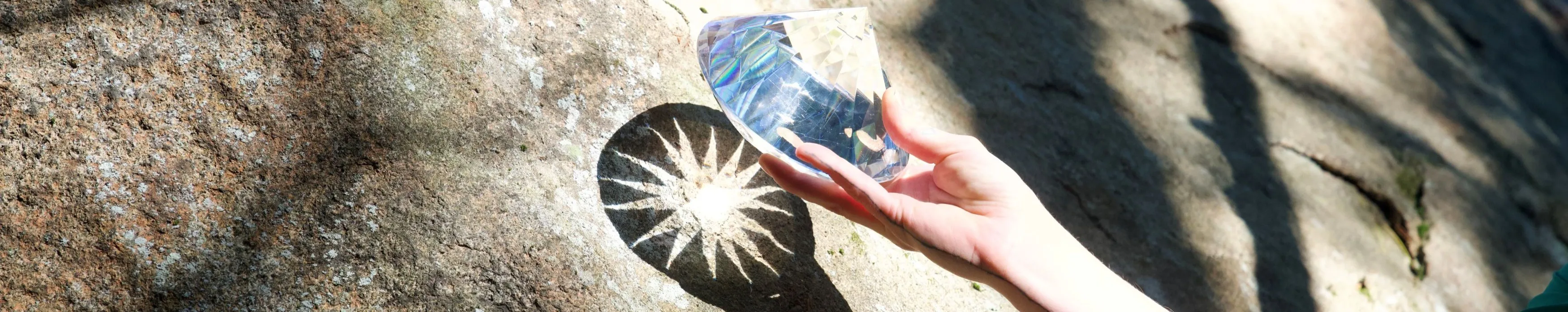 diamond prism held by Vanessa Hale, casting a sun shaped shadow